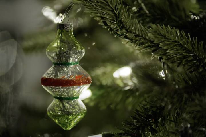 Glass ornament hangs from a Christmas tree.