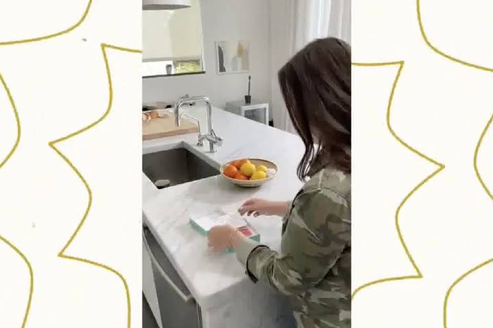 Woman opens up a small gift in her kitchen